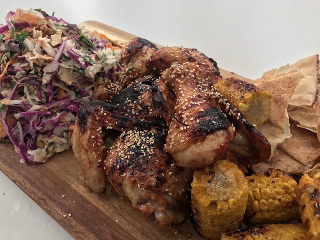 Πιάτο με ψημένα παϊδάκια κοτόπουλο BBQ, Coleslaw με κόκκινο και λευκό λάχανο, και καλαμπόκι βουτυρωμένο με κύμινο