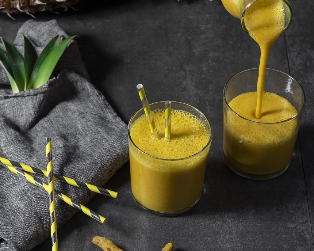 Ποτήρι με κρεμώδες Smoothie ανανά, κουρκουμά και καρύδα, διακοσμημένο με σπόρους chia και φρέσκο ανανά