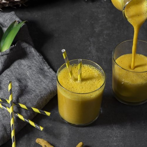 Ποτήρι με κρεμώδες Smoothie ανανά, κουρκουμά και καρύδα, διακοσμημένο με σπόρους chia και φρέσκο ανανά