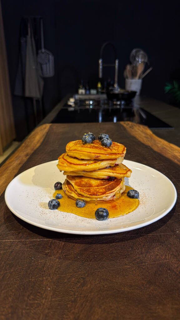 Αφράτα cottage cheese pancakes με blueberries σε πιάτο, περιχυμένα με θυμαρίσιο μέλι