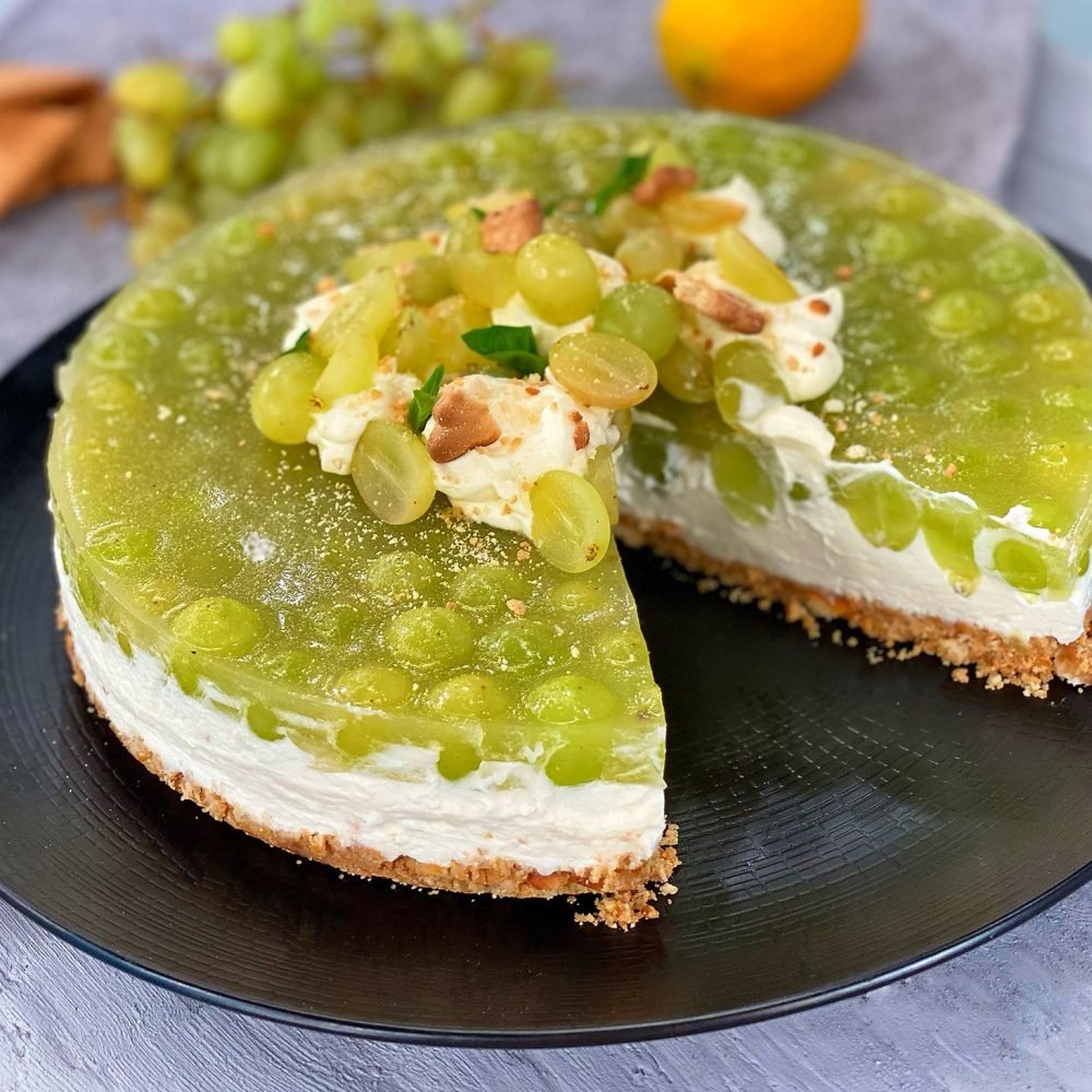 150 γρ. μπισκότα τύπου πτι-μπερ 80 γρ. βούτυρο (λιωμένο) 450 γρ. φυτική κρέμα 20% λιπαρά 300 γρ. τυρί κρέμα 100 γρ. άχνη ζάχαρη 5 μικρά φύλλα ζελατίνης 1 κιλό σταφύλια πράσινα χωρίς κουκούτσι 60 γρ. ζάχαρη χυμό από μισό λεμόνι