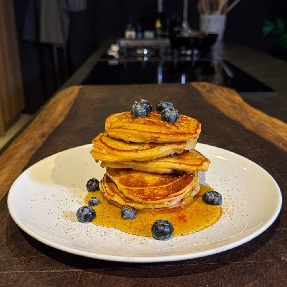 Αφράτα cottage cheese pancakes με blueberries σε πιάτο, περιχυμένα με θυμαρίσιο μέλι